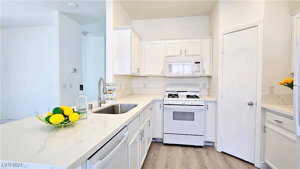 kitchen with light hardwood / wood-style flooring, white appliances, light stone countertops, white cabinetry, and sink