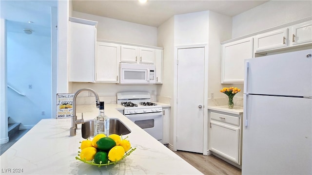 kitchen with light hardwood / wood-style flooring, sink, white appliances, and white cabinetry