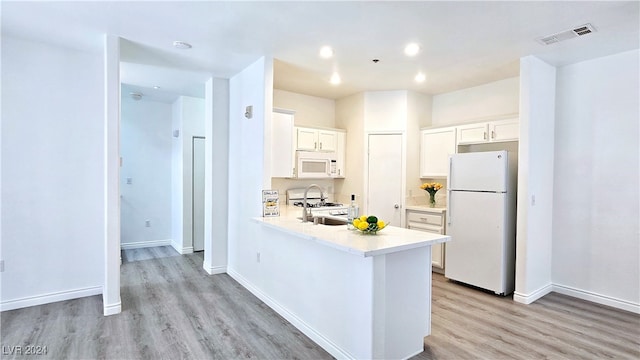 kitchen featuring light hardwood / wood-style flooring, kitchen peninsula, white appliances, and white cabinets