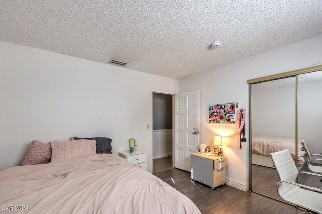 bedroom with a textured ceiling, a closet, and dark hardwood / wood-style floors