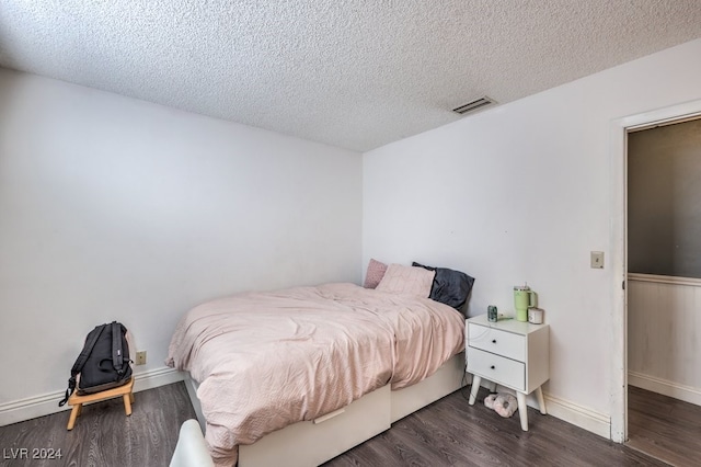 bedroom with a textured ceiling and dark wood-type flooring