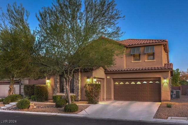 mediterranean / spanish home with driveway, an attached garage, central AC, stucco siding, and a tiled roof