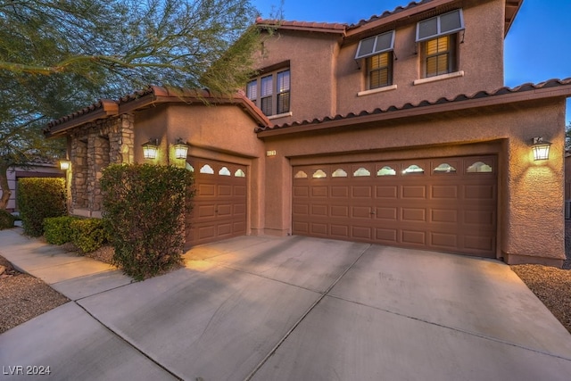 mediterranean / spanish-style home featuring stucco siding, concrete driveway, a garage, stone siding, and a tile roof