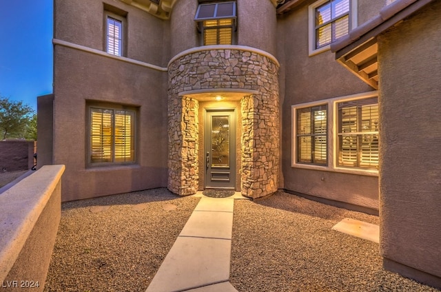 entrance to property featuring stone siding and stucco siding