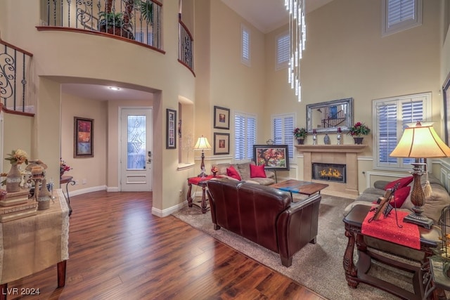 living area featuring a glass covered fireplace, baseboards, arched walkways, and wood finished floors