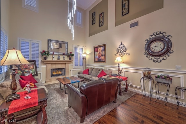 living room with dark hardwood / wood-style flooring, a tile fireplace, and a high ceiling