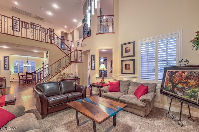 living room with visible vents, stairs, a towering ceiling, and wood finished floors