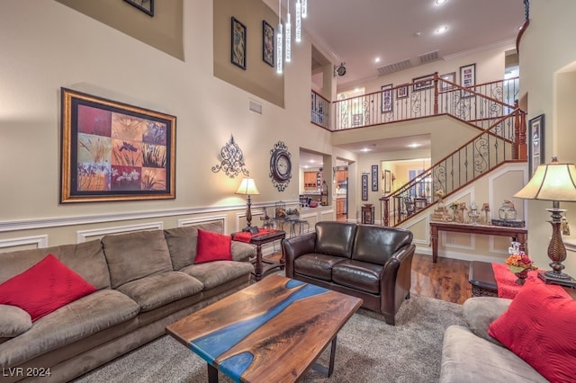 living room featuring a high ceiling, hardwood / wood-style floors, and ornamental molding