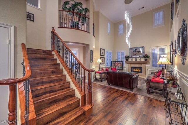 staircase featuring a high ceiling, ornamental molding, and hardwood / wood-style flooring