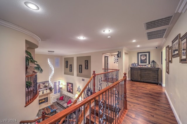 corridor featuring crown molding, wood finished floors, an upstairs landing, and visible vents