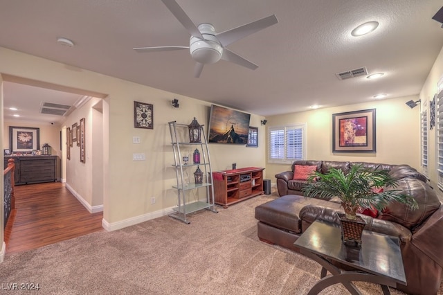 carpeted living room with ceiling fan and a textured ceiling