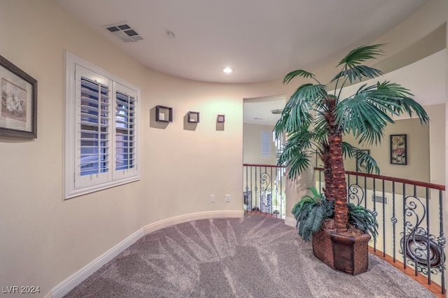 hallway with visible vents, baseboards, and carpet flooring