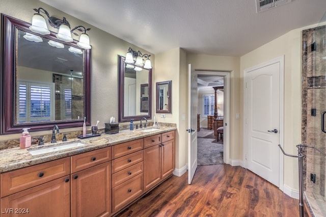 bathroom featuring a sink, visible vents, wood finished floors, and a shower stall