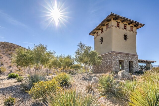 view of side of property featuring a tiled roof, stone siding, and stucco siding