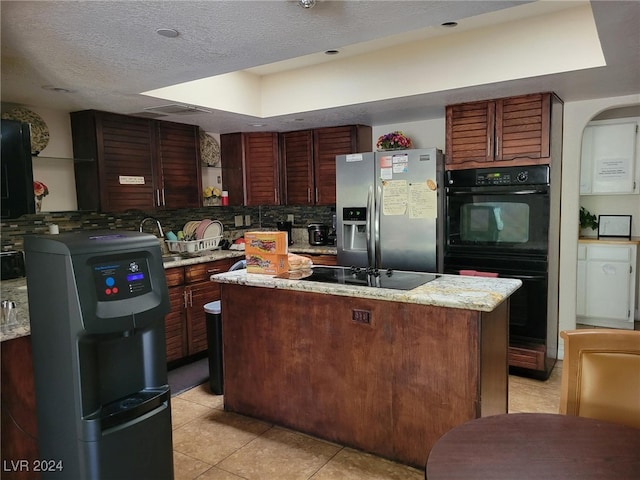 kitchen featuring black appliances, tasteful backsplash, a kitchen island, and light tile patterned floors