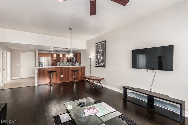 living room featuring ceiling fan with notable chandelier and dark wood-type flooring