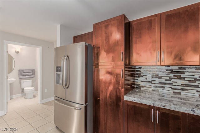 kitchen with light tile patterned floors, backsplash, and stainless steel refrigerator with ice dispenser