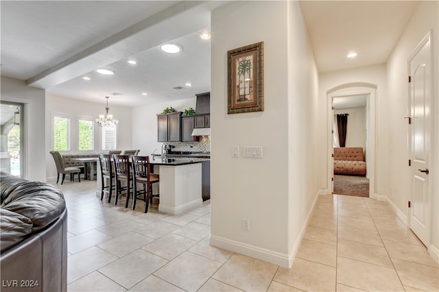 hall with an inviting chandelier and light tile patterned flooring