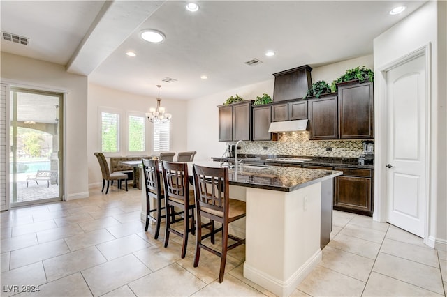 kitchen featuring a notable chandelier, sink, an island with sink, hanging light fixtures, and a breakfast bar