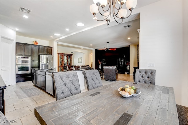 dining area with ceiling fan with notable chandelier, sink, and light tile patterned flooring