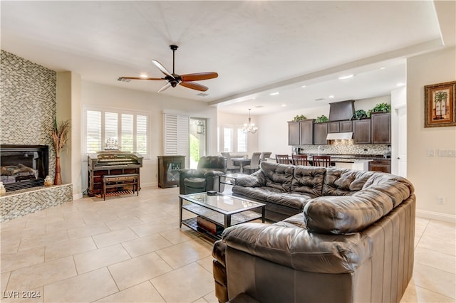 tiled living room with plenty of natural light, a tiled fireplace, and ceiling fan with notable chandelier