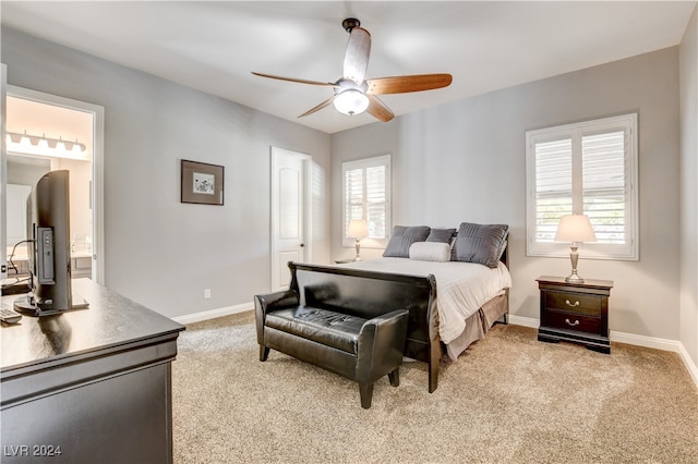 bedroom with multiple windows, light colored carpet, connected bathroom, and ceiling fan