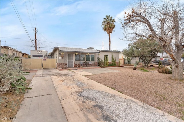 view of front of property featuring brick siding, fence, concrete driveway, a gate, and stucco siding