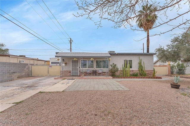 back of property featuring brick siding, a gate, and stucco siding