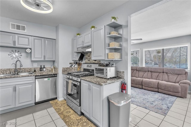 kitchen with visible vents, appliances with stainless steel finishes, light stone counters, under cabinet range hood, and a sink