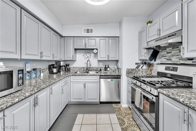 kitchen featuring light tile patterned floors, stainless steel appliances, visible vents, a sink, and under cabinet range hood