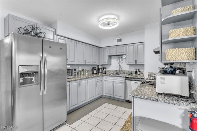 kitchen with light tile patterned floors, stainless steel appliances, open shelves, visible vents, and a sink