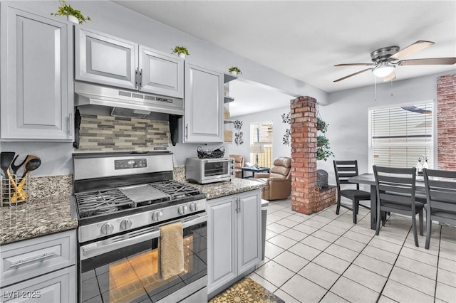 kitchen with light tile patterned floors, a toaster, under cabinet range hood, stainless steel gas range, and decorative columns