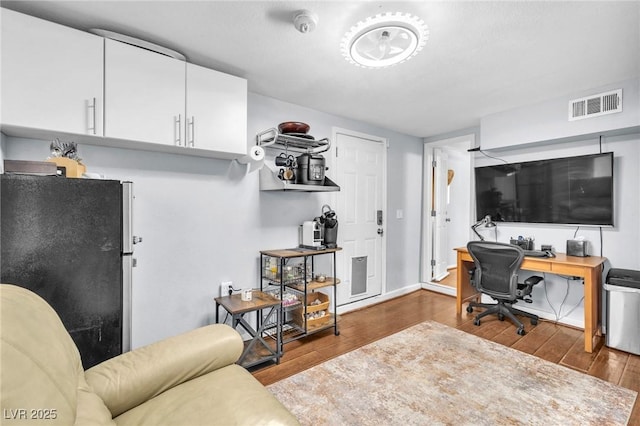 office space featuring wood-type flooring, visible vents, and baseboards