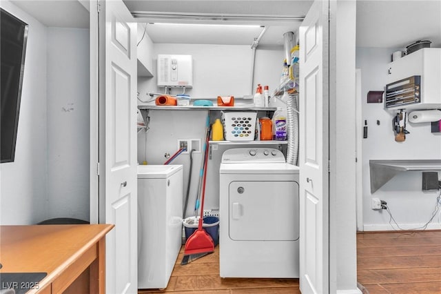 laundry area with laundry area, washing machine and clothes dryer, and wood finished floors