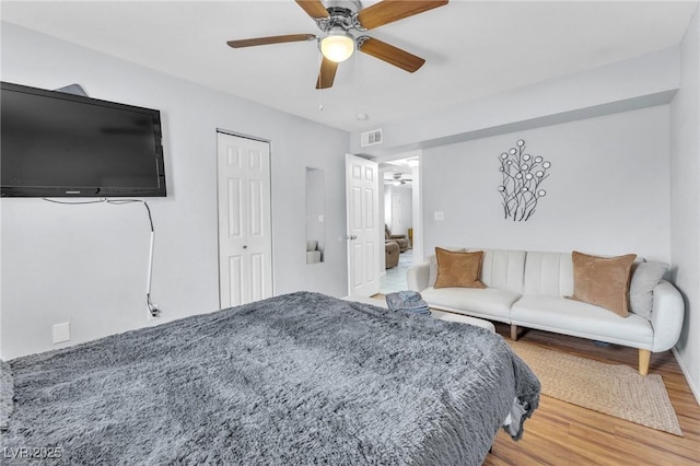 bedroom with a ceiling fan, a closet, visible vents, and wood finished floors