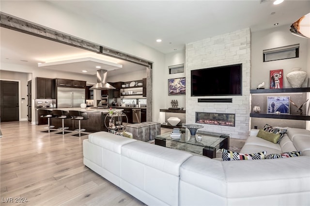 living room with light hardwood / wood-style flooring and a stone fireplace