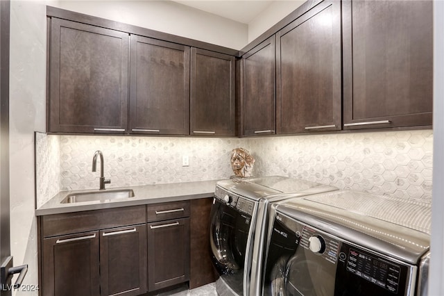 clothes washing area with washer and dryer, cabinets, and sink