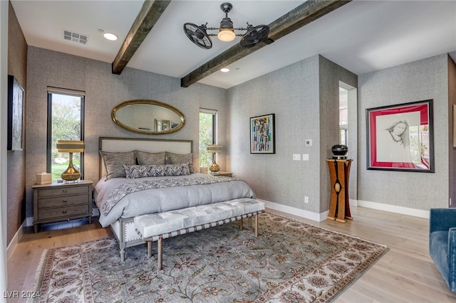 bedroom with ceiling fan, beam ceiling, multiple windows, and hardwood / wood-style flooring