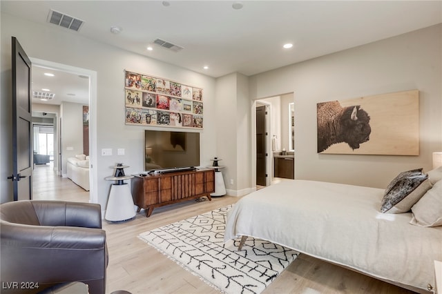 bedroom with light hardwood / wood-style flooring and ensuite bath