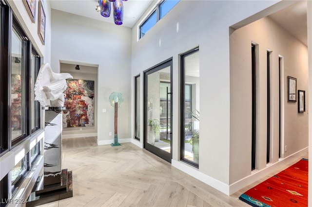 doorway featuring a towering ceiling and light parquet flooring