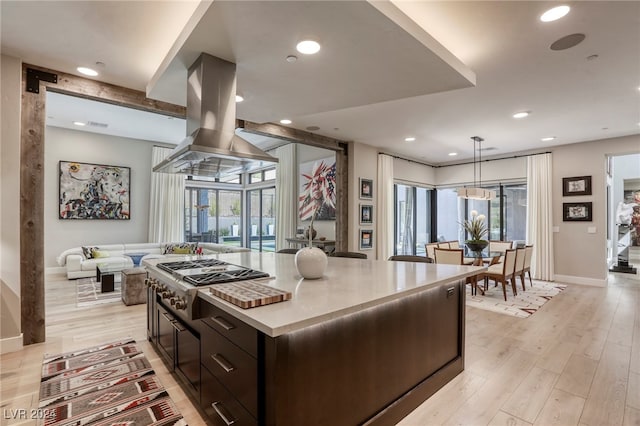 kitchen with stainless steel gas stovetop, hanging light fixtures, light hardwood / wood-style flooring, a kitchen island, and island range hood