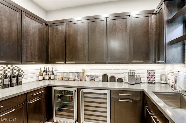 interior space with dark brown cabinetry, backsplash, wine cooler, and sink