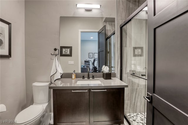 bathroom featuring vanity, toilet, and a shower with shower door