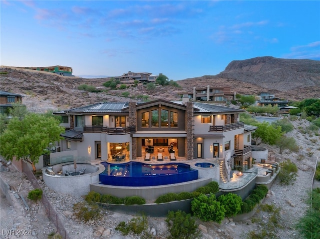 back house at dusk featuring a balcony and a mountain view