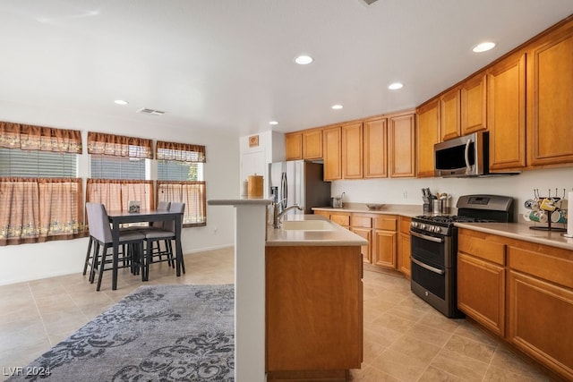 kitchen featuring stainless steel appliances, sink, and an island with sink