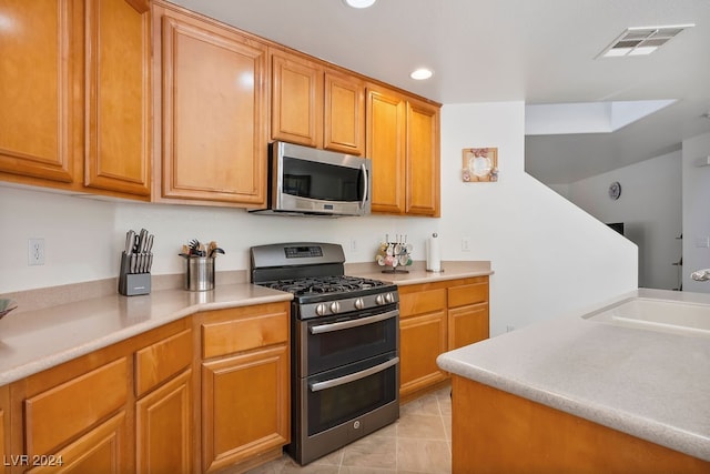 kitchen featuring light tile patterned flooring, stainless steel appliances, and sink