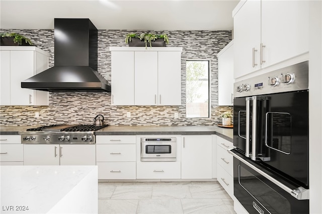 kitchen with wall chimney range hood, white cabinets, stainless steel gas cooktop, and tasteful backsplash