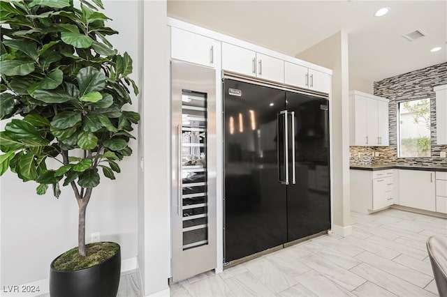 kitchen featuring tasteful backsplash, white cabinetry, wine cooler, and black built in refrigerator