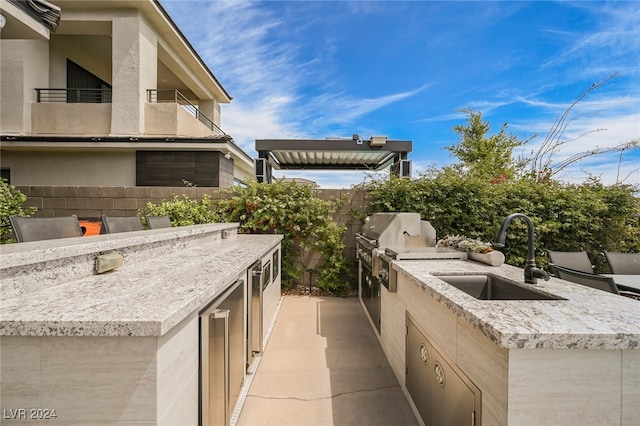 view of patio featuring a balcony, grilling area, an outdoor kitchen, and sink