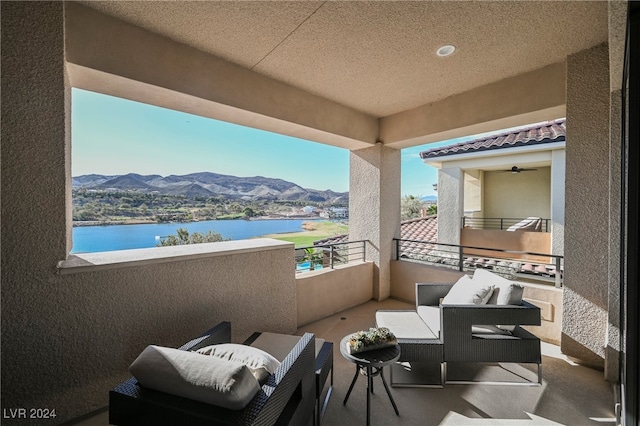 balcony with an outdoor living space and a water and mountain view